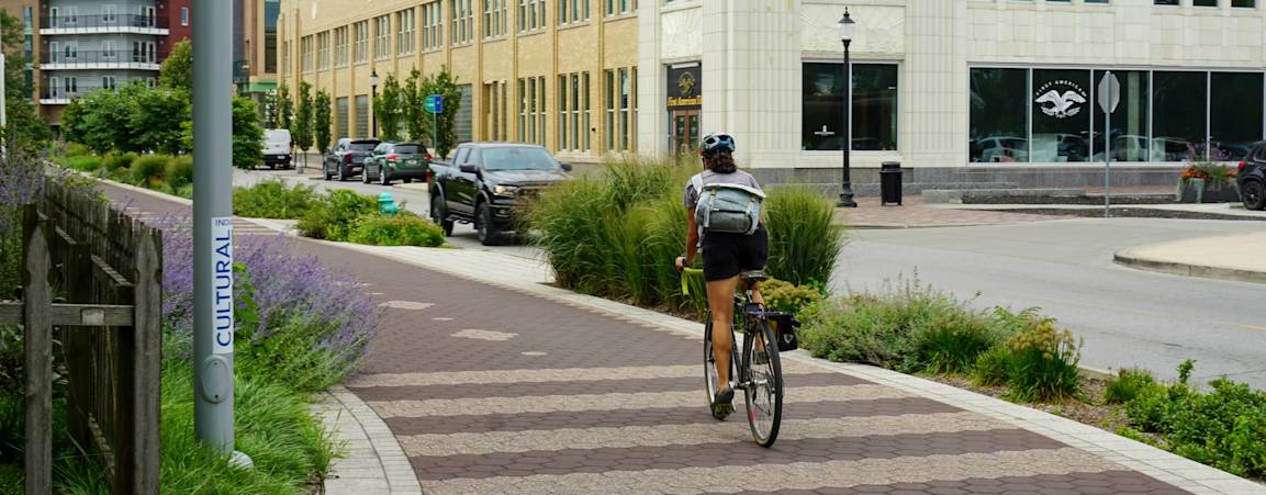 A woman commutes on a bike path in a city landscape