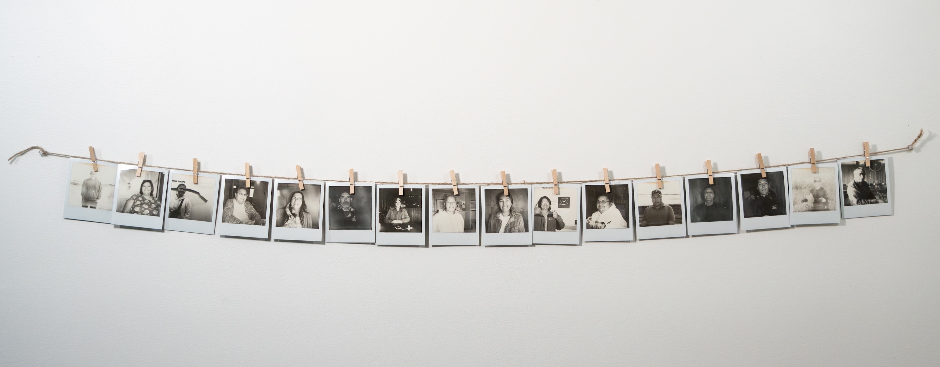 String of polaroid photos hung with clothespins. Shows the Elders of Churchill. 