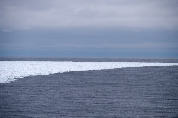 A small band of sea ice curves into open ocean waters.