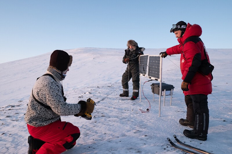 Researchers set up a camera and solar panels near a polar bear den site